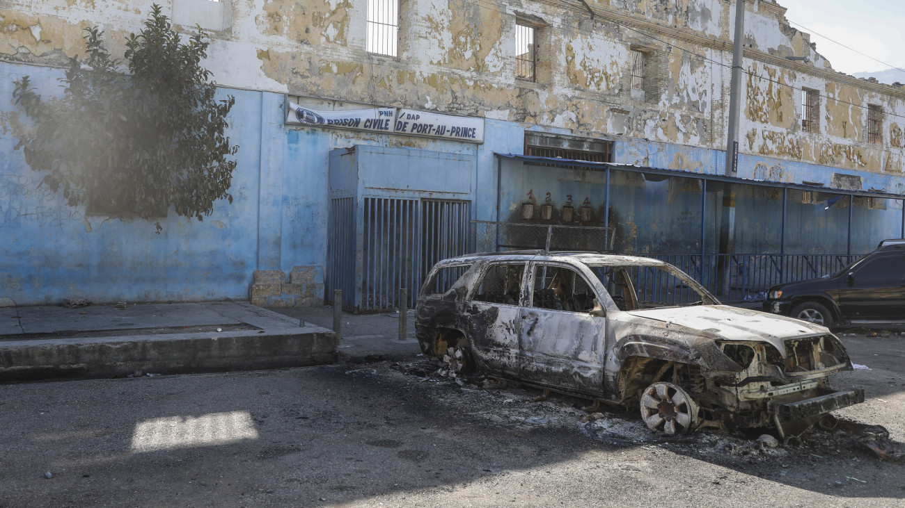Kiégett autóroncs a haiti főváros, Port-au-Prince fegyintézeténél 2024. március 3-án, miután reggelre virradóan fegyveres bandák törtek be a börtönbe. Az akció során többen életüket vesztették, és rabok százai szöktek meg. A haiti kormány szükségállapotot hirdetett. Az utóbbi időben a helyi bűnbandák összehangolt támadásokat hajtottak végre a káoszba süllyedt karibi szigetország rendvédelmi szervei ellen.