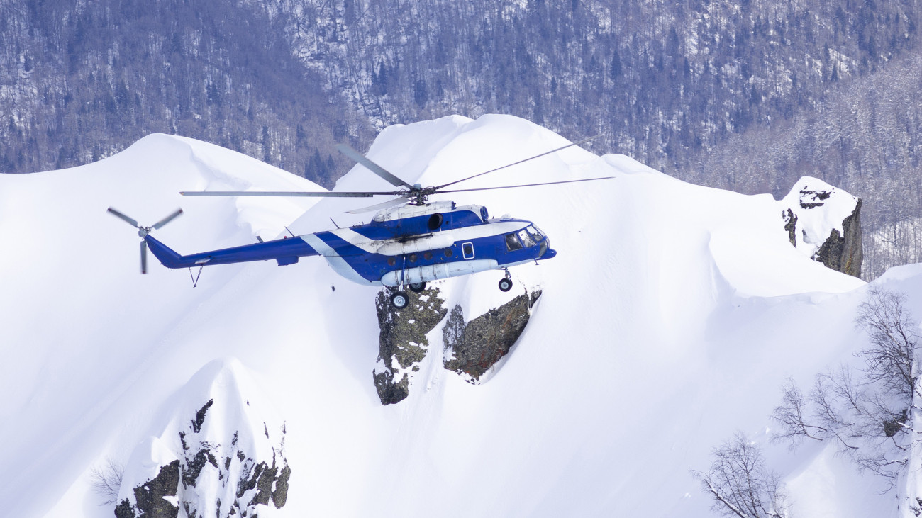 Russian helicopter Mil Mi-8 flying over snowy mountains in Caucasus, near Krasnaya Polyana for heliskiing purposes.