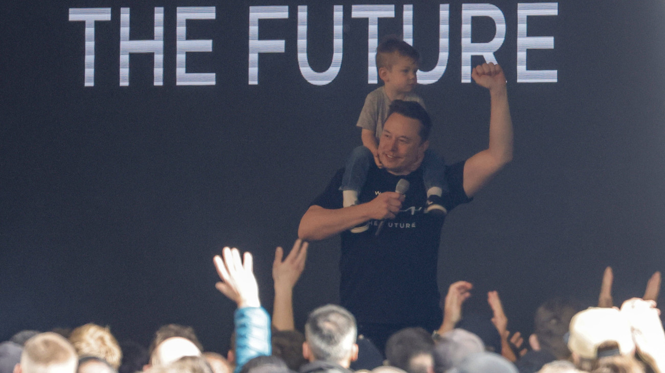 Elon Musk, a Tesla Motors vezérigazgatója a kisfiával, X AE A-XII-vel a vállán színpadra lép a cég németországi, grünheidei gyárában 2024. március 13-án. Nyolc nappal korábban a baloldali szélsőséges Vulkán Csoport megtámadta a gyár áramellátó rendszerét, emiatt akkor leállt a termelés.