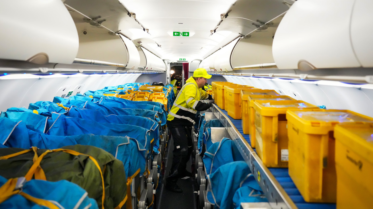 PRODUCTION - 27 March 2024, Brandenburg, SchĂśnefeld: A WISAG employee pushes yellow plastic boxes full of letters and other mail into the front of the cabin of an Airbus A320-214 at Berlin Brandenburg Airport (BER). The passenger seats were previously covered with fabric sleeves, into which the mailboxes were then strapped.  After more than 62 years, Deutsche Post has discontinued its domestic mail flights. Early Thursday morning, the last plane took off from Berlin and flew to Stuttgart. Shortly before, planes had taken off from Hanover, Munich and Stuttgart. The six planes were carrying only letters - a total of around 1.5 million items weighing 53 tons. Photo: Soeren Stache/dpa (Photo by Soeren Stache/picture alliance via Getty Images)