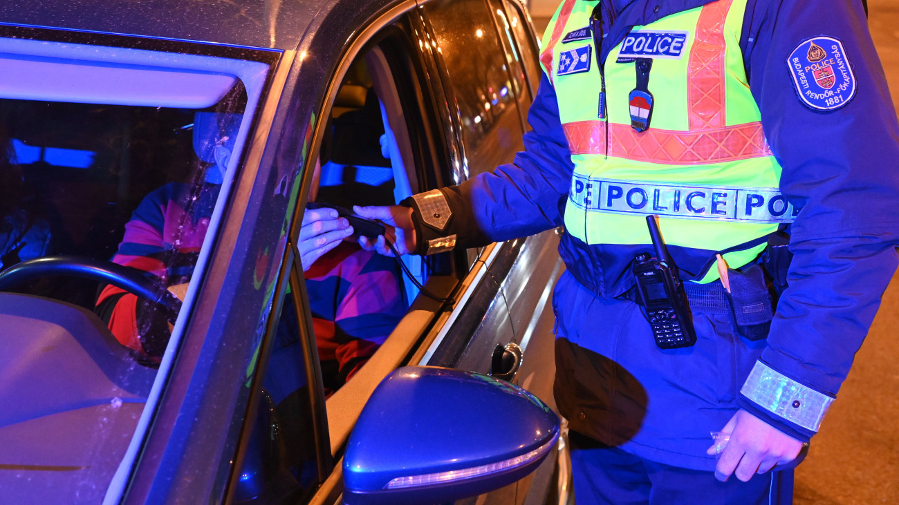 Járművezetőt szondáztat egy rendőr Budapesten, a Váci út elején 2022. április 17-én. Országszerte közúti ellenőrzéseket tartanak húsvétkor, a rendőrök az ittas vezetők kiszűrésére koncentrálnak.