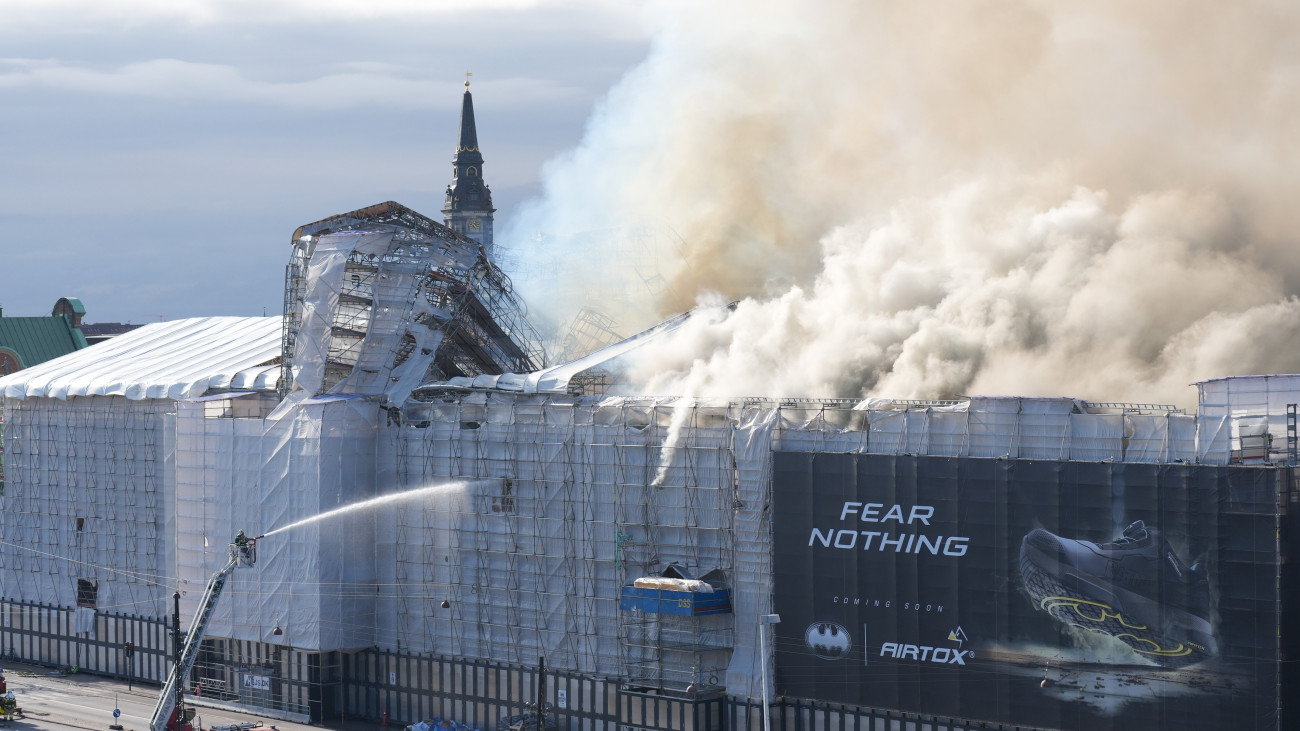 Tűzoltók küzdenek a lángok megfékezésén a felújítás alatt álló régi Tőzsdepalotánál Koppenhágában 2024. április 16-án.