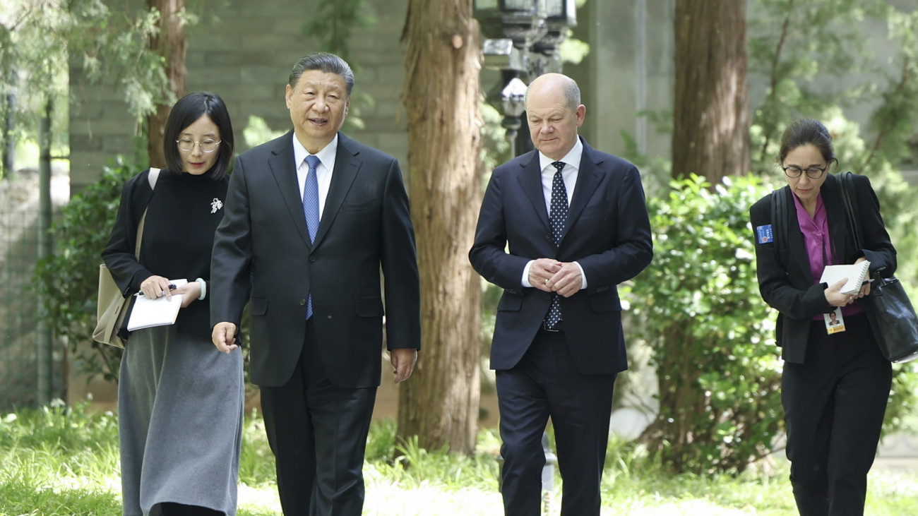 A Hszinhua kínai állami hírügynökség felvételén Hszi Csin-ping kínai elnök (b2) és Olaf Scholz német kancellár (j2) sétál a pekingi Tiaojütaj állami vendégház kertjében 2024. április 16-án.