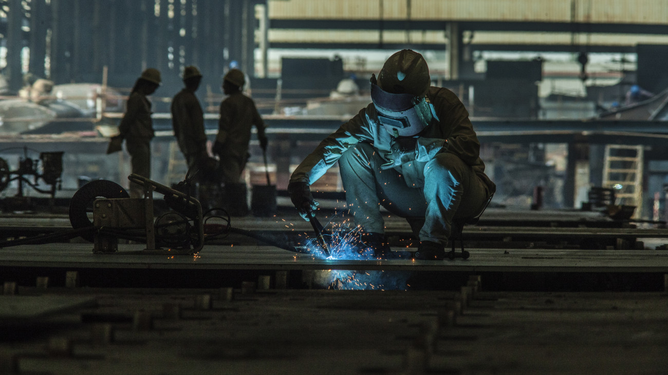 Sparks fly in the dark from a welder in a metal factory.