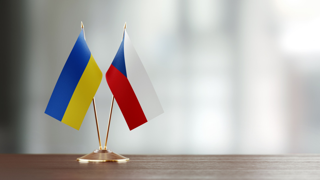 Ukrainian and Czechoslovakian flag pair on desk over defocused background. Horizontal composition with copy space and selective focus.