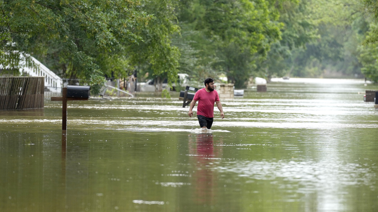 Vízben gázol egy férfi az esőzések által elárasztott texasi Woodloch településen 2024. május 4-én.