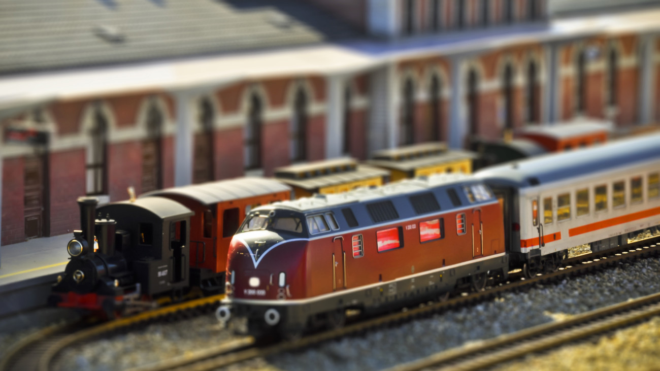 Perfect models of the older (steam) and newer (diesel) locomotives and passenger trains wait on the railway station. Tilt-shift technique.