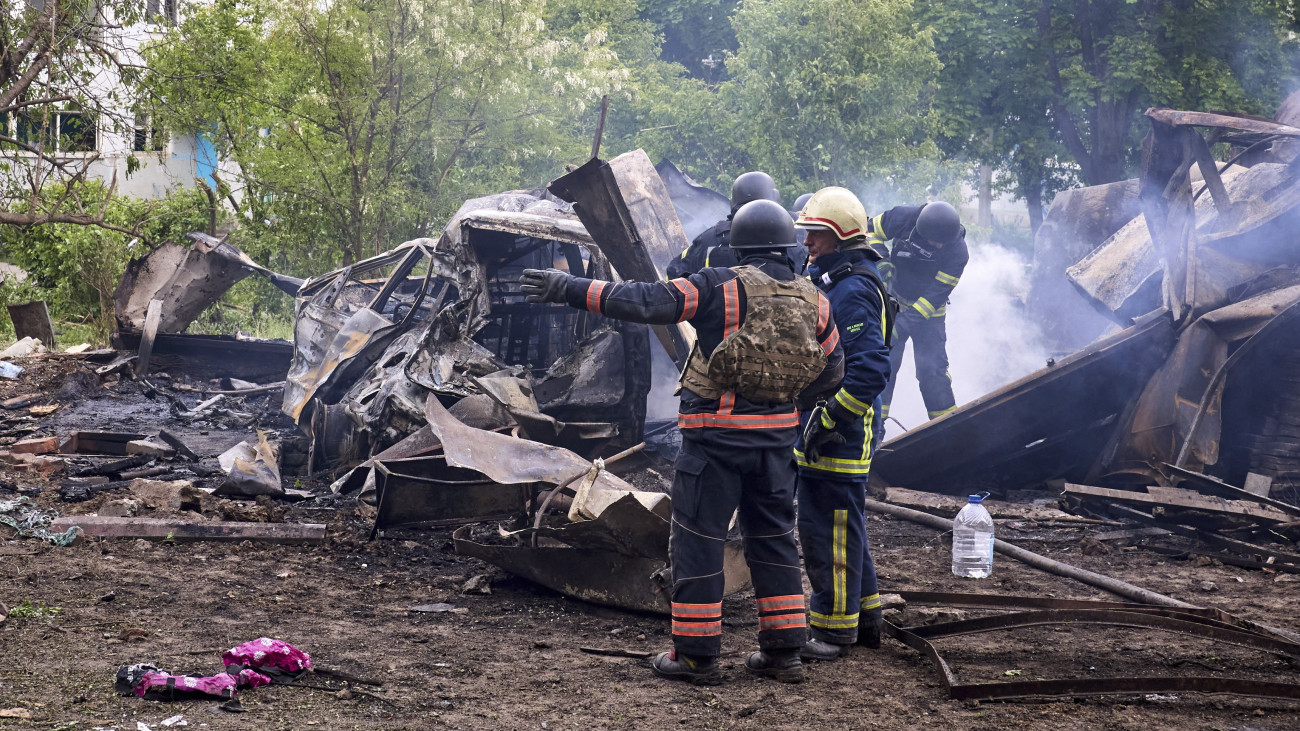 Kiégett autóroncsok mellett mentők Harkivban 2024. május 14-én, miután orosz rakéta-és siklóbomba-támadás érte a kelet-ukrajnai város egyik lakónegyedét. Ukrán források szerint legalább 20 ember, köztük 3 gyermek megsebesült.