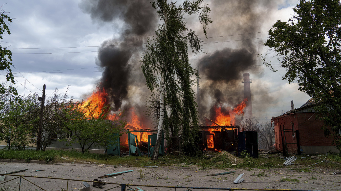 Lakóépületek lángolnak orosz légicsapások után a Harkiv megyei Vovcsanszk településen 2024. május 11-én.