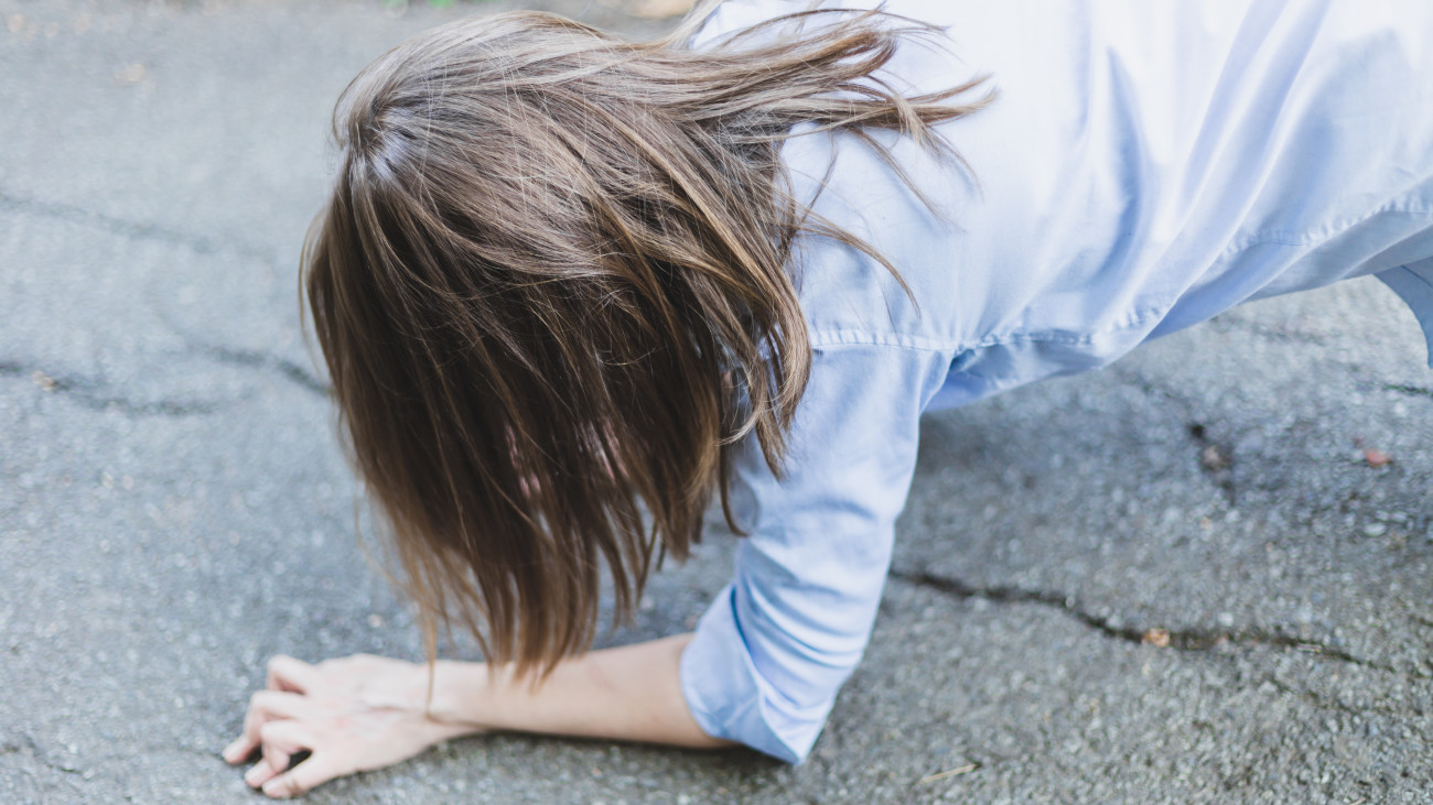 Young woman with heart problems lying on the ground facing down - Girl with chest pain faint on the street - Female with epilepsy in need for help