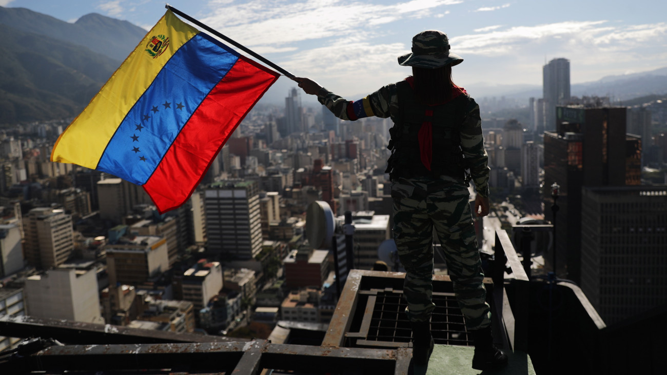 A venezuelai zászlót lenget egy gyakorlatozó katona Caracasban 2020. február 15-én. Venezuela csapatokat, páncélozott és csapatszállító járműveket vont össze február 13-án a Kolumbiával szomszédos határon a Nicolás Maduro államfő parancsára elrendelt hadgyakorlatokra. A katonai manővereket február 15-16-án tartják az ország különböző térségeiben levő nagyvárosokban, egy esetleges amerikai agresszióval számolva.