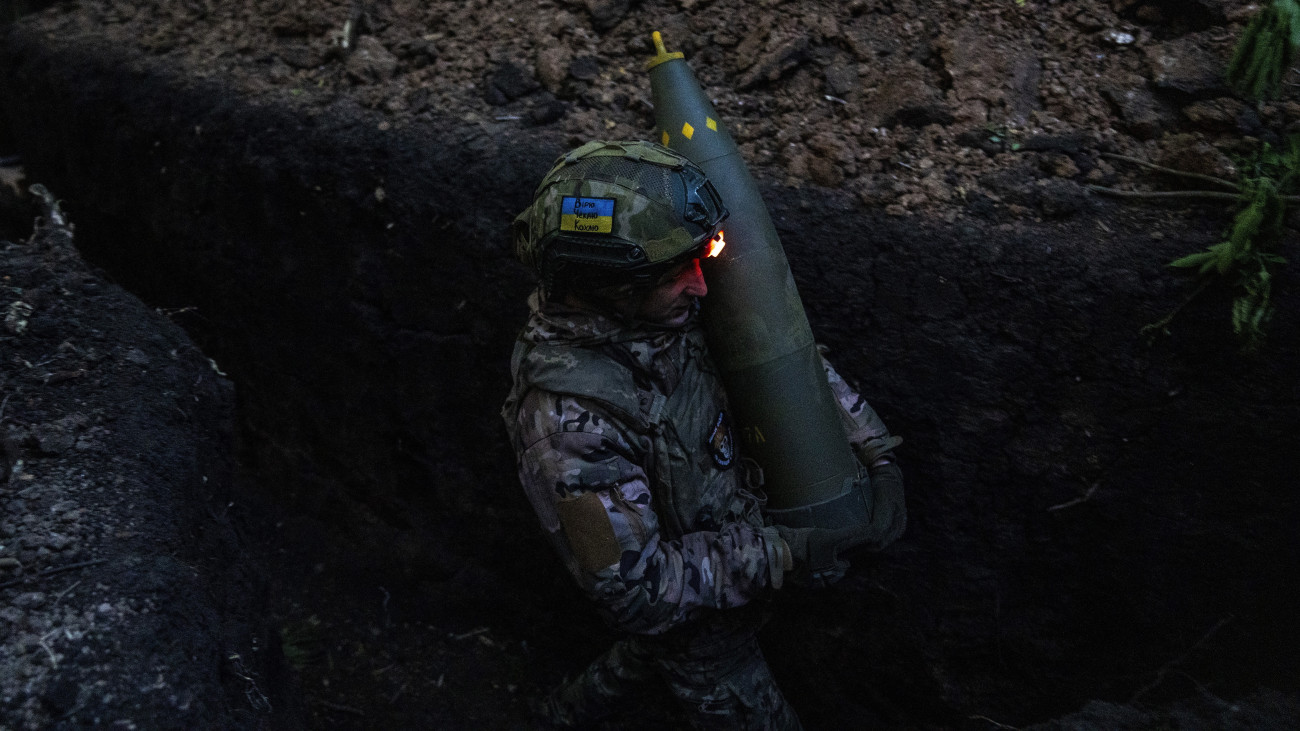 Ukrán tüzér lövedéket visz, amint bajtársaival az orosz állások ágyúzására készül a kelet-ukrajnai Donyecki területen húzódó fronton 2024. május 6-án.