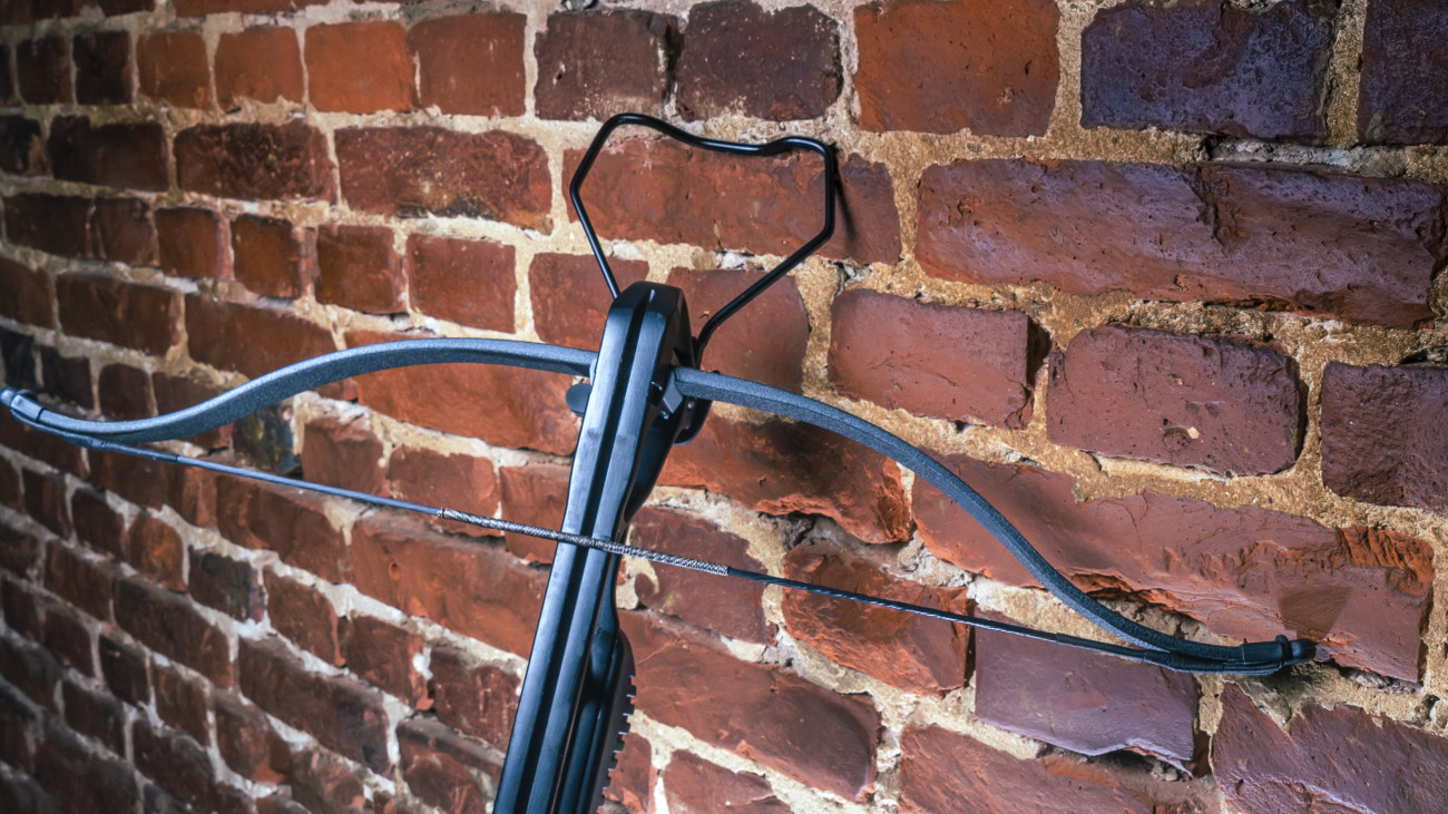 A modern compound crossbow handgun on the red brick wall background.