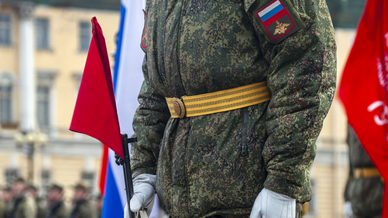 Field military uniform of Russian soldier at parade rehearsal against the background of the colors of the national flag. Details of clothing and equipment of an officer with weapon at parade training on Palace Square in St. Petersburg.