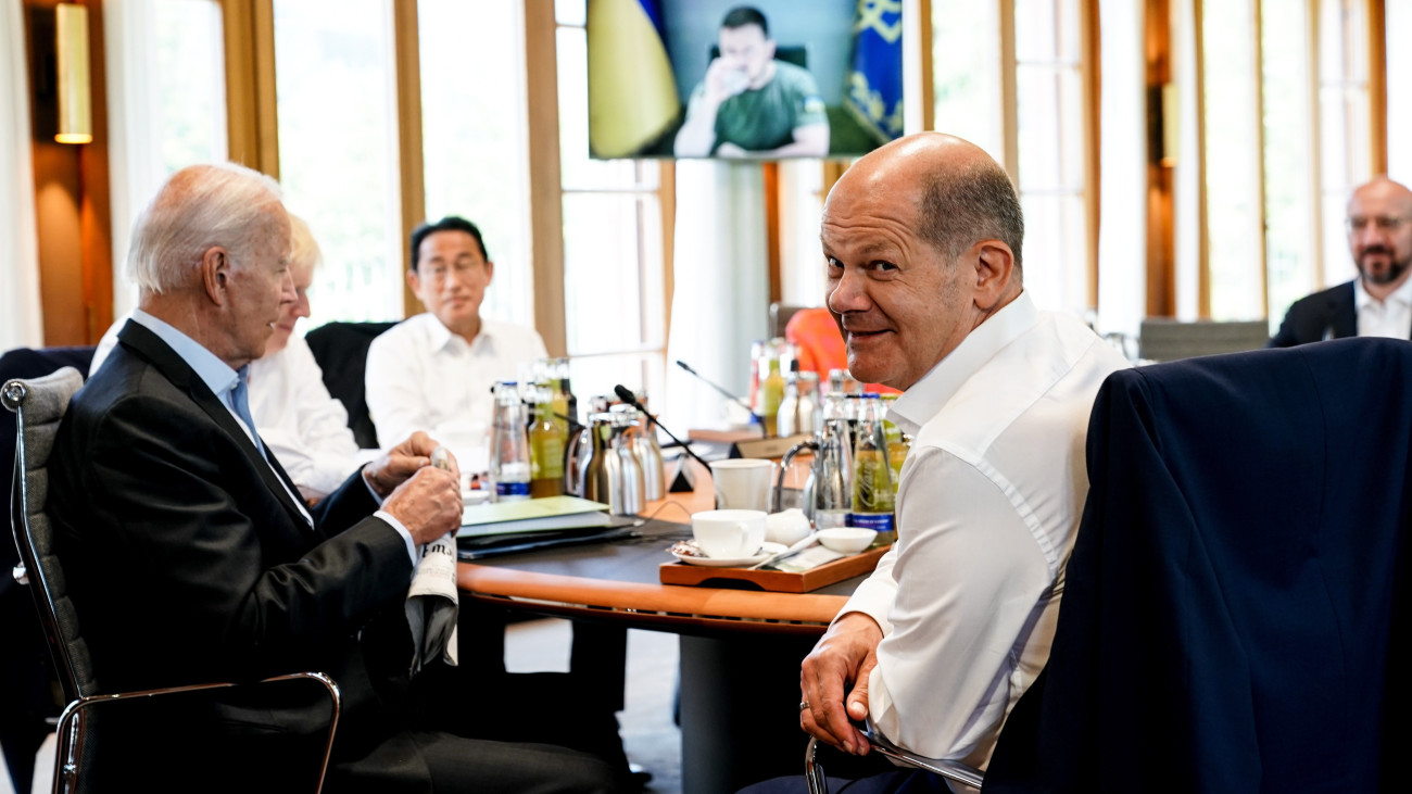 Joe Biden amerikai elnök (b), Kisida Fumio japán miniszterelnök (b2) és Olaf Scholz német kancellár (j2) a világ hét legfejlettebb ipari országát tömörítő G7-csoport csúcstalálkozóján, a kivetítőn Volodimir Zelenszkij ukrán elnök a Garmisch-Partenkirchen közelében levő Elmau-kastélyban 2022. június 27-én.