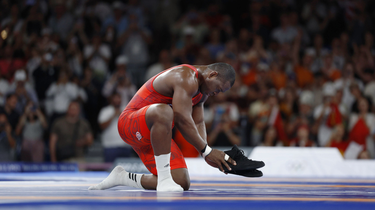 Mijain Lopez Nunez of Cuba takes off his shoes and places them on the mat after winning the wrestling mens Greco-Roman 130-kilogram final at the Paris Olympics on Aug. 6, 2024, at Champ-de-Mars Arena in Paris to become the first athlete to win five consecutive Olympic gold medals in the same individual event. He said he is retiring after the Olympics. (Photo by Kyodo News via Getty Images)