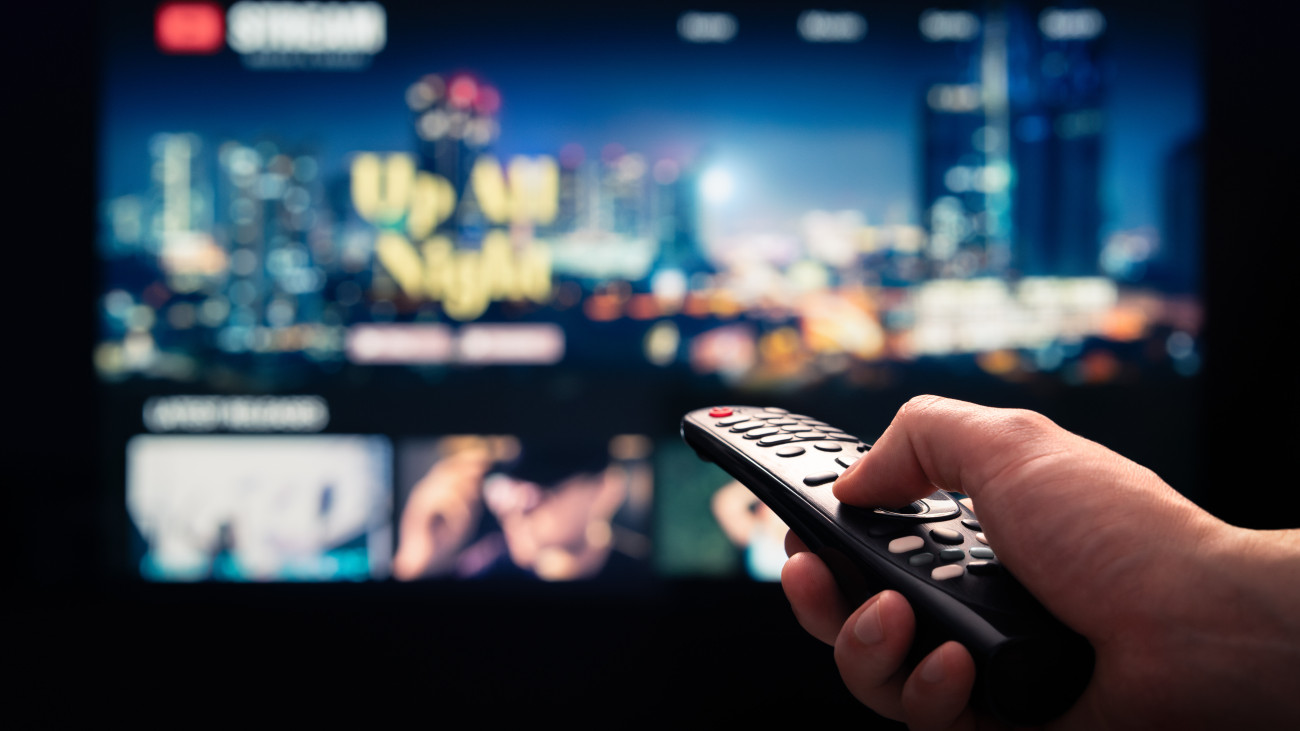 Watching movie stream service on tv. Video on demand subscription service and platform in television. Streaming series, films and shows online. Man using remote control. Person browsing mockup VOD.