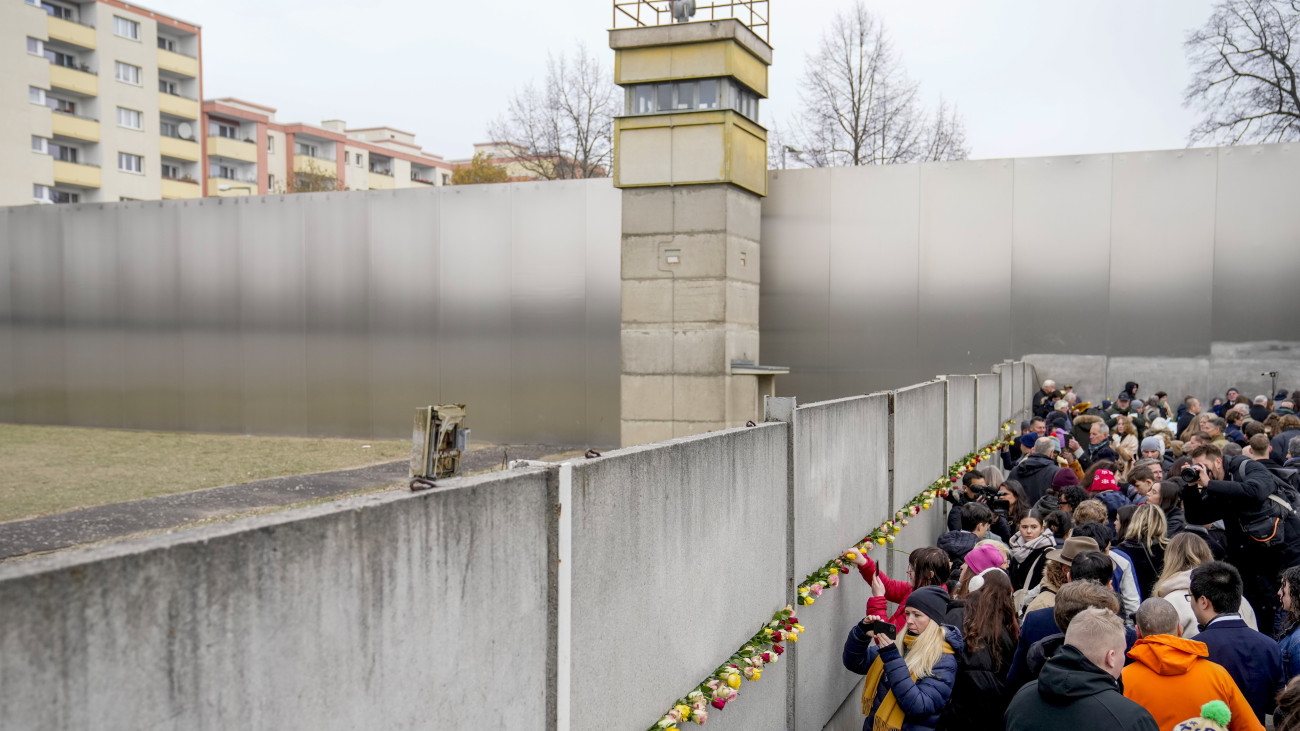 Emberek virágokat helyeznek el az egykori berlini fal megmaradt részénél a fal ledöntésének 35. évfordulója alkalmából rendezett megemlékezésen 2024. november 9-én.