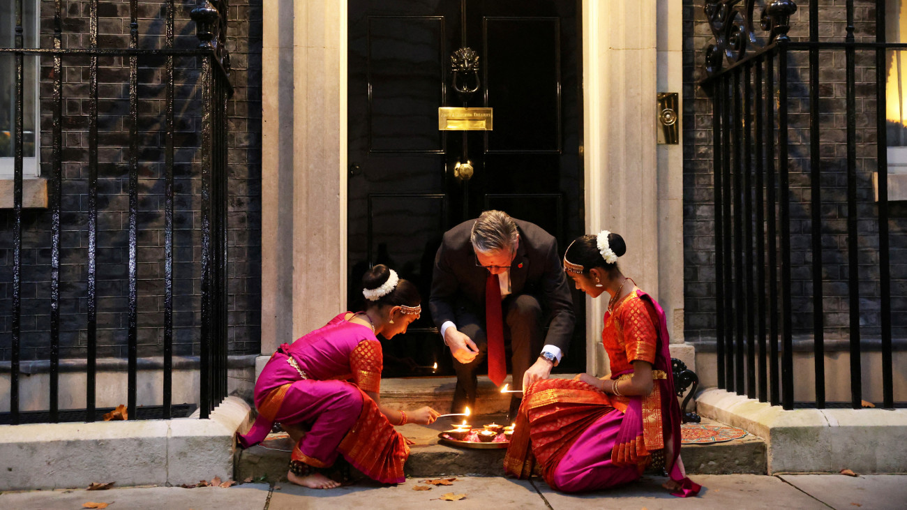 LONDON, ENGLAND - OCTOBER 29: Britains Prime Minister Keir Starmer and members of the Arunima Kumar Dance Company light candles at the doorstep of 10 Downing Street at a reception at 10 Downing Street to celebrate Diwali on October 29, 2024 in in London, England. Diwali is the Hindu Festival of Light, also known as Deepawali, and symbolizes the spiritual victory of light over darkness, good over evil, and knowledge over ignorance. (Photo by Mina Kim - WPA Pool/Getty Images)