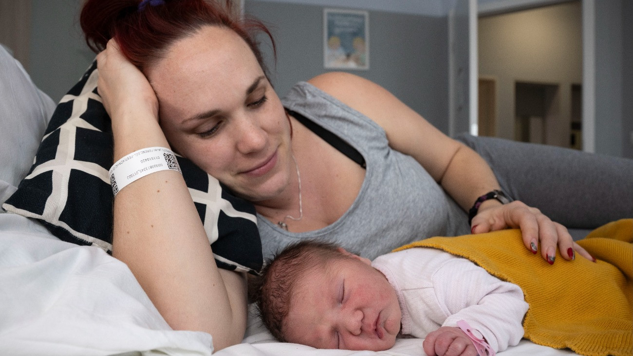 A fõváros elsõ újévi babája, Jónás Liza anyjával, Jónás Renátával a Budapesti Jahn Ferenc Kórház és Rendelõintézet szülészeti osztályán 2026. január 1-jén. A kislány éjfél után négy perccel született, 3370 grammal és 52 centiméterrel, természetes úton, édesanyja második gyermekeként.